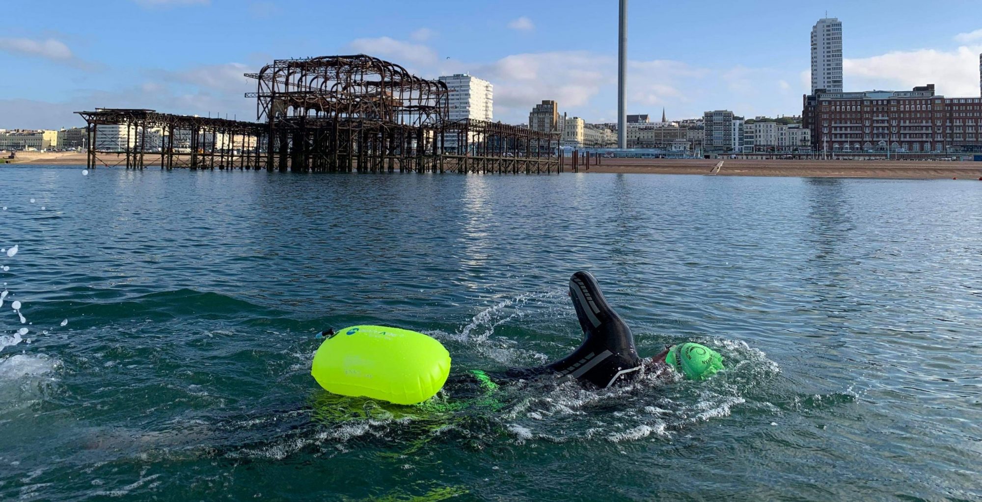 Triathlete swimming in the sea towing a bright yellow sea float